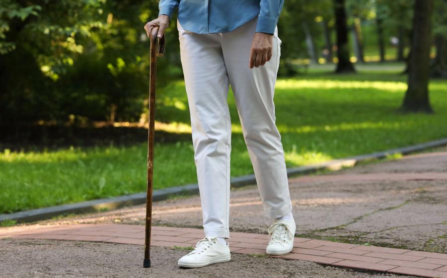 Woman walking with a cane along a sidewalk